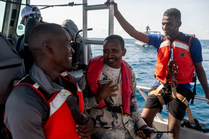Three people smile as they talk on board a boat