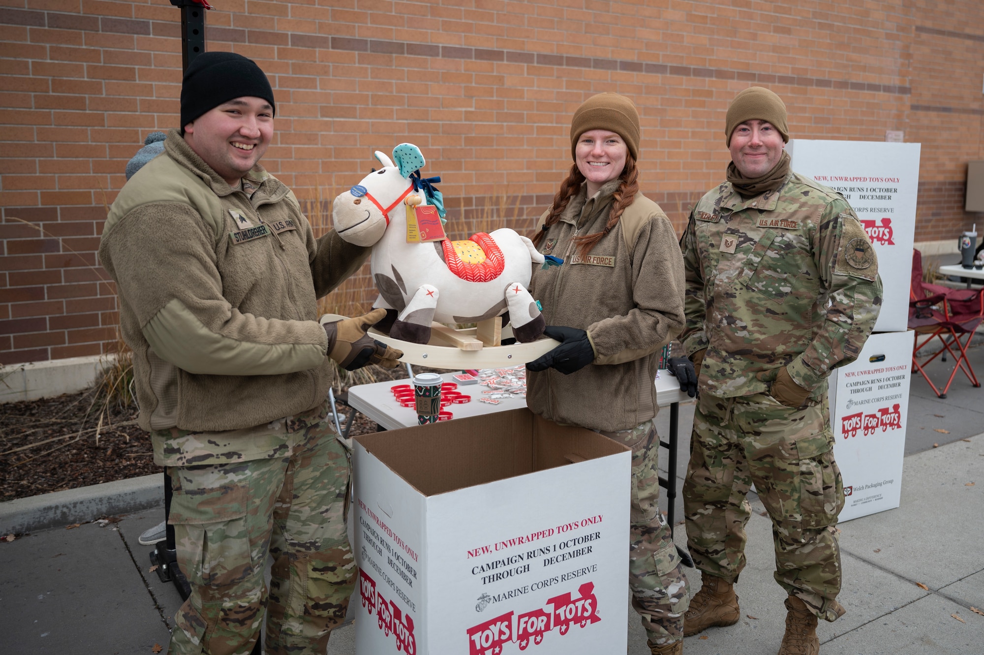 Airmen pose with a toy from a toys for tots drive.