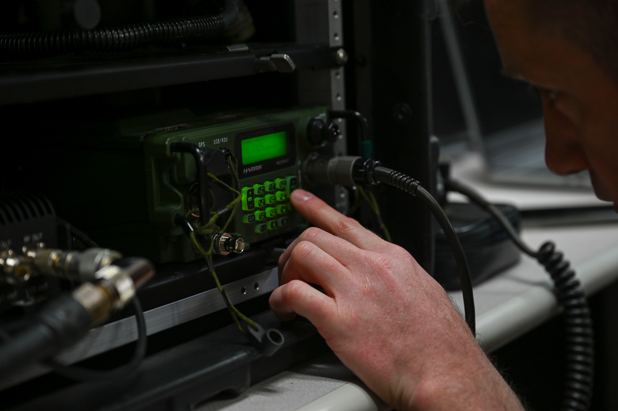 An Airman types on a keypad of a portable radio system.