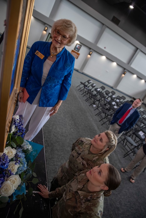 Dr. Lucy looks at her portrait with Airmen