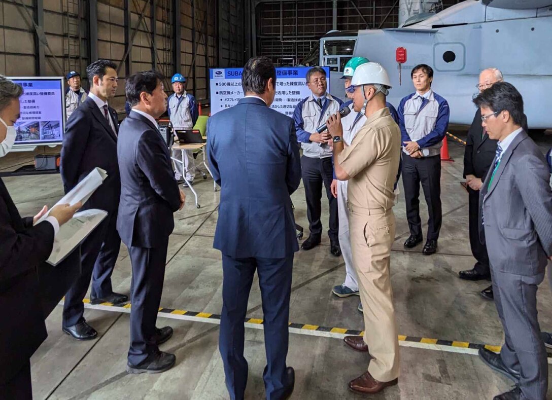 Group of people gather in an aircraft hangar.