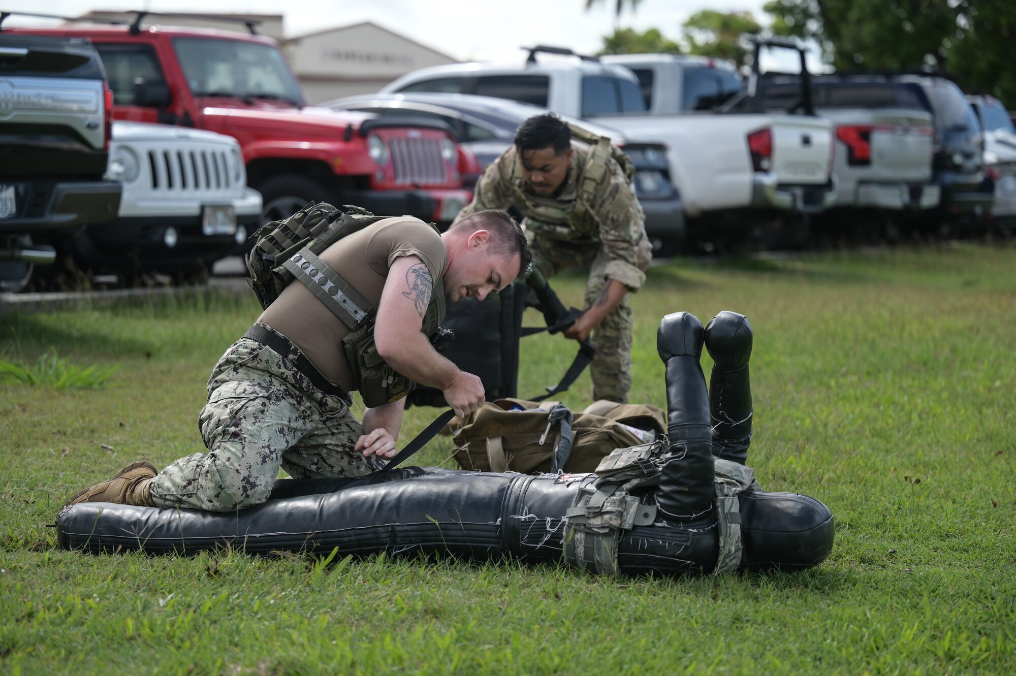 U.S. Navy Master-at-Arms 1st Class Mitchell Cayea, Joint Base Pearl Harbor-Hickam Police Services noncommissioned officer, and U.S. Air Force Staff Sgt. Xavier Laxa, 647th Security Forces Squadron Police Services noncommissioned officer in-charge, performs tactical combat casualty care during a fire team challenge on Joint Base Pearl Harbor-Hickam, Hawaii, May 14, 2024. Several components during the challenge tested JBPHH Airmen and Sailor’s capabilities to enact skills within the fastest cumulative time. (U.S. Air Force photo by Staff Sgt. Alan Ricker)