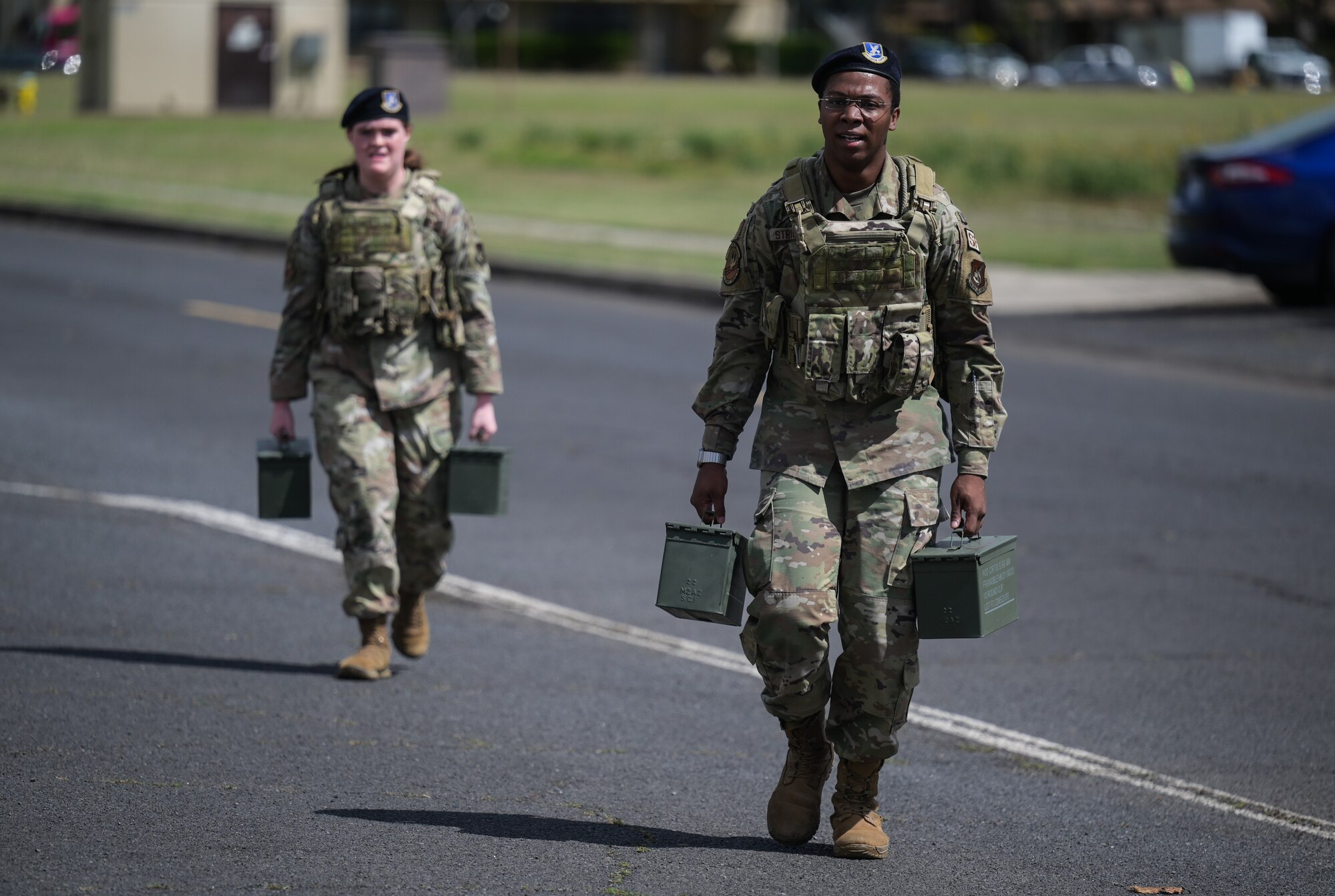 Two Airmen carry ammo boxes.