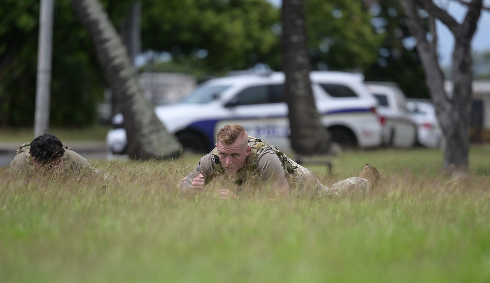 An Airman performs a low crawl in the grass.
