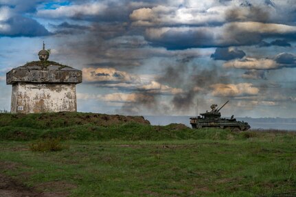 A soldier stands on top of a tank.
