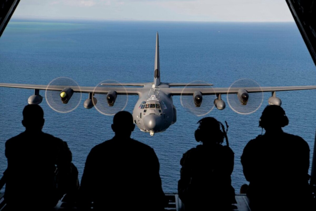 Service members are seated on the ramp of a military aircraft while in flight.