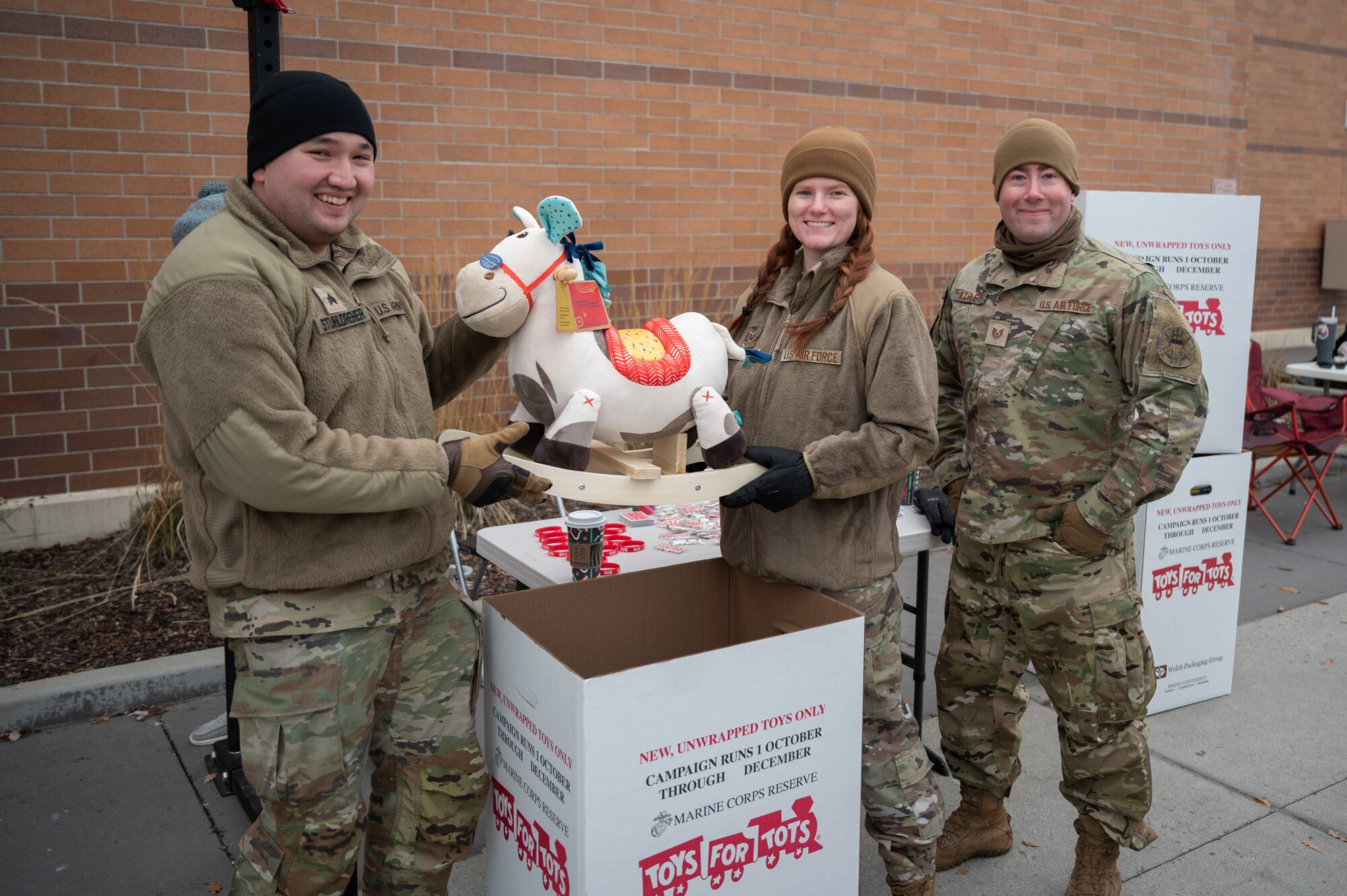 Airmen pose with a toy from a toys for tots drive.