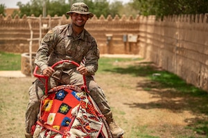 A U.S. Air Force Airman assigned to the 378th Air Expeditionary Wing rides a camel during a Saudi Arabian Culture Day at an undisclosed location within the U.S. Central Command area of responsibility, May 11, 2024. Culture Day provided valuable professional exchanges between Saudi citizens and Airmen. (U.S. Air Force photo)
