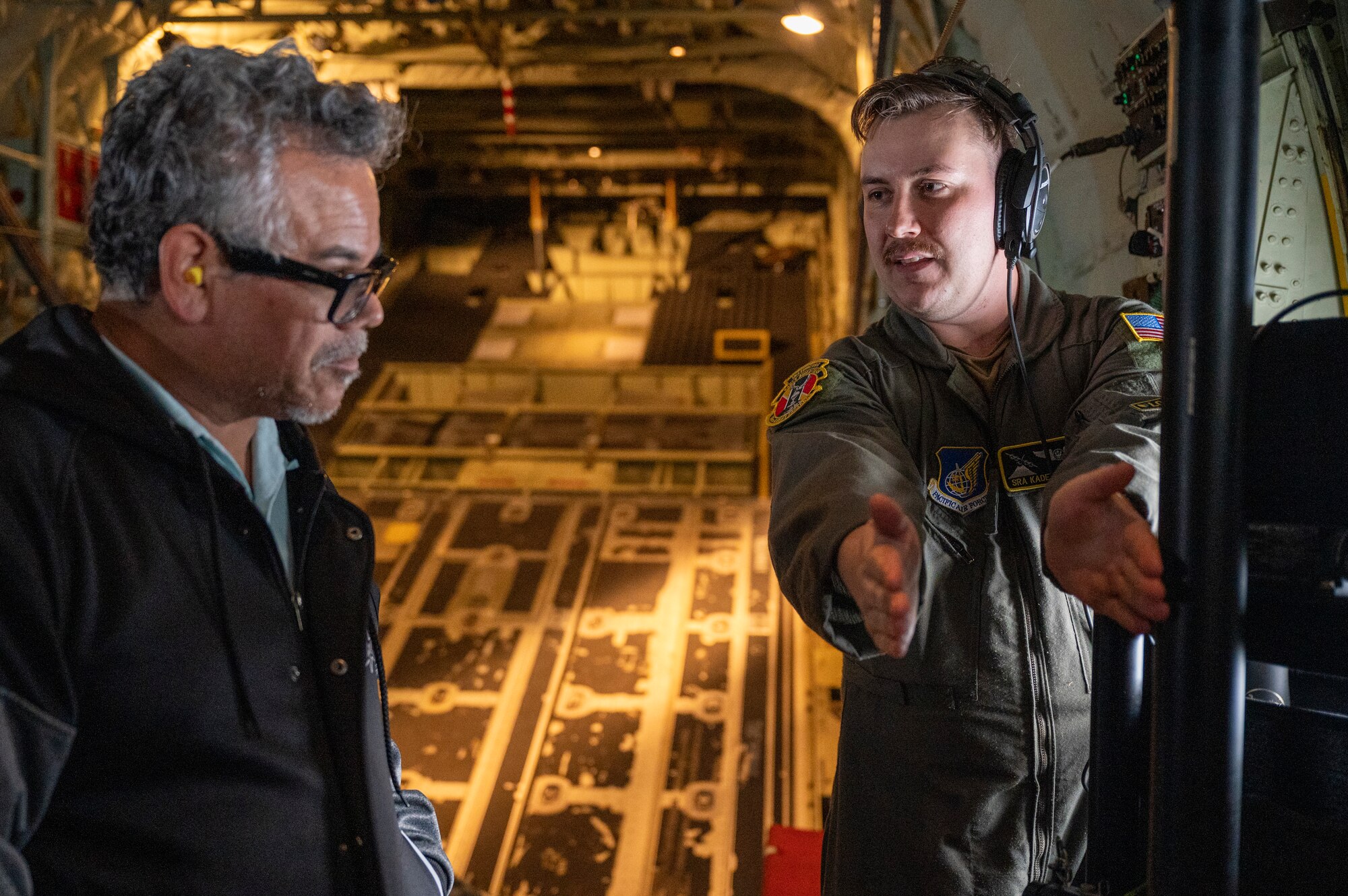 A loadmaster talks to a teacher inside a C-130J Super Hercules.
