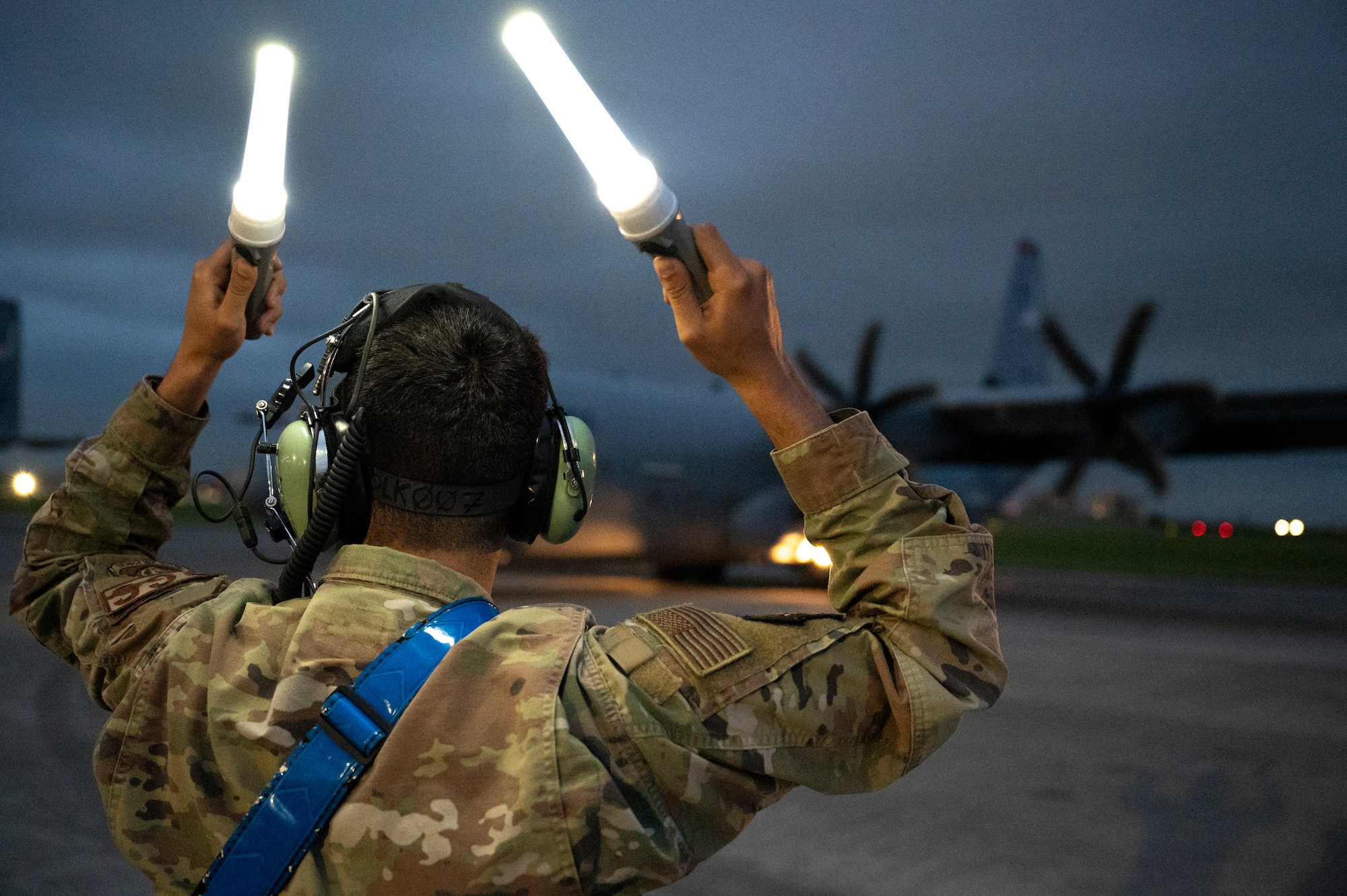 An airman marshals a C-130J Super Hercules