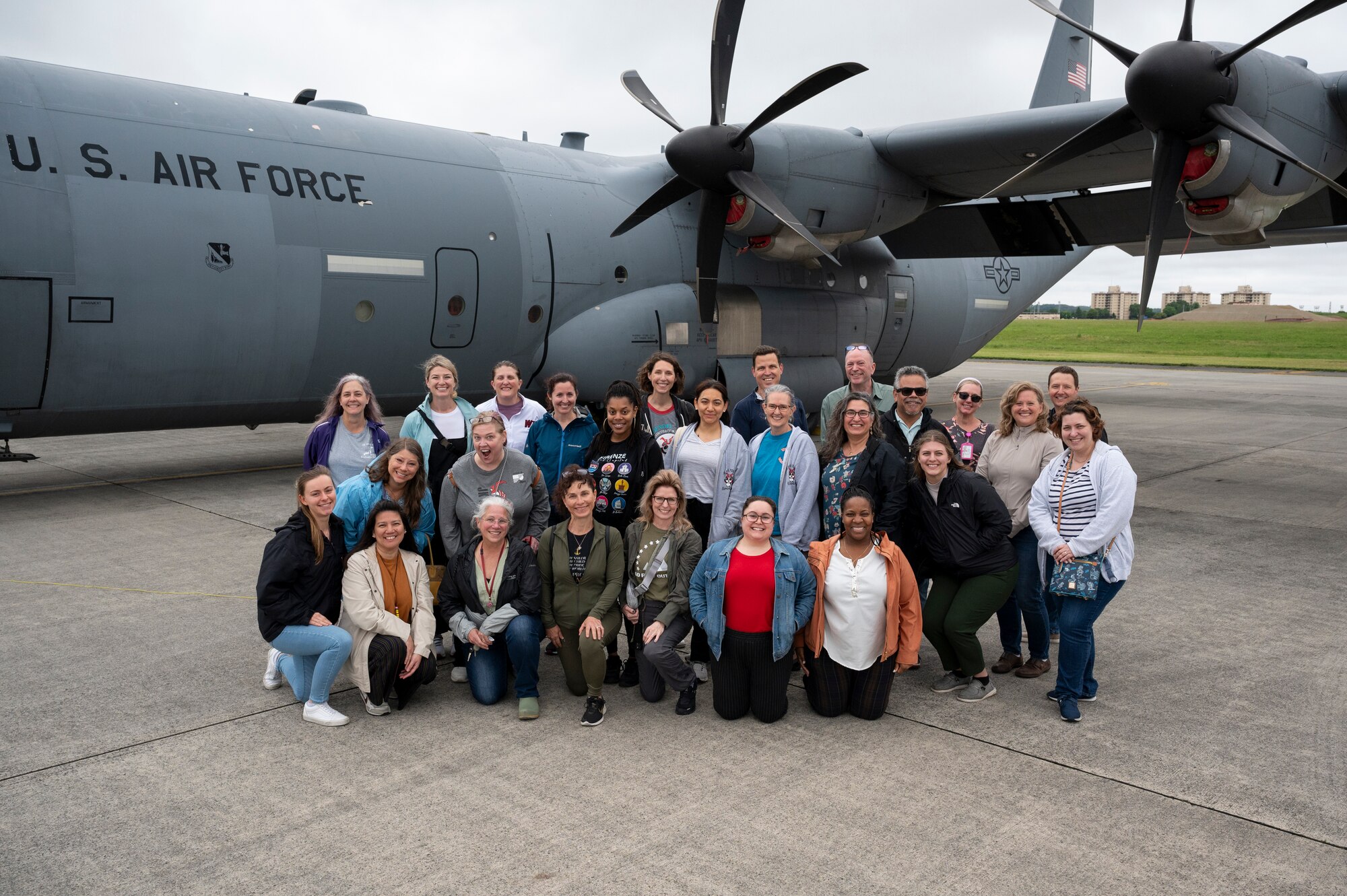 Teachers pose for a photo in front of a C-130J Super Hercules.