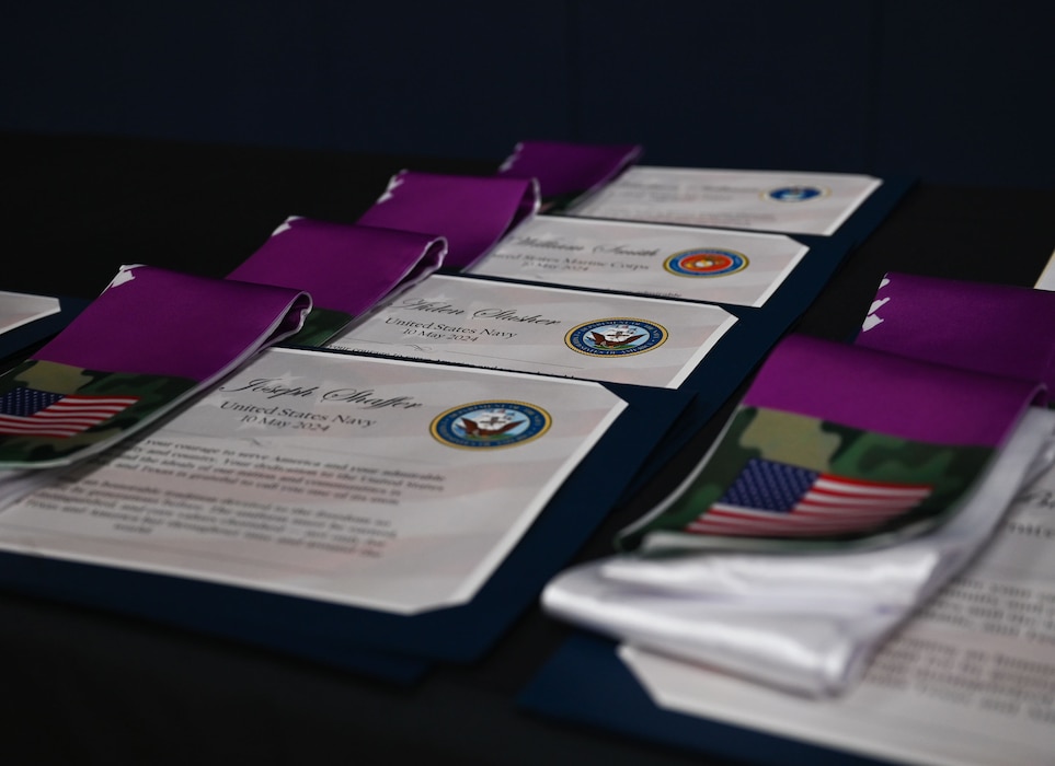 Military commitment certificates and graduation stoles sit on a table at the second annual Goodfellow Air Force Base Armed Forces Commitment Celebration at the Mathis Fitness Center, Goodfellow Air Force Base, Texas, May 10, 2024. After their name was called and the students declared what branch of service they selected, they received a certificate and stole. (U.S. Air Force photo by Airman First Class Evelyn J. D’Errico)