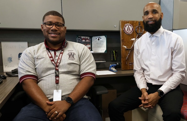 Environmental of two men sitting in a cubicle. They are both African Americans and alumni of Alabama A&M University.