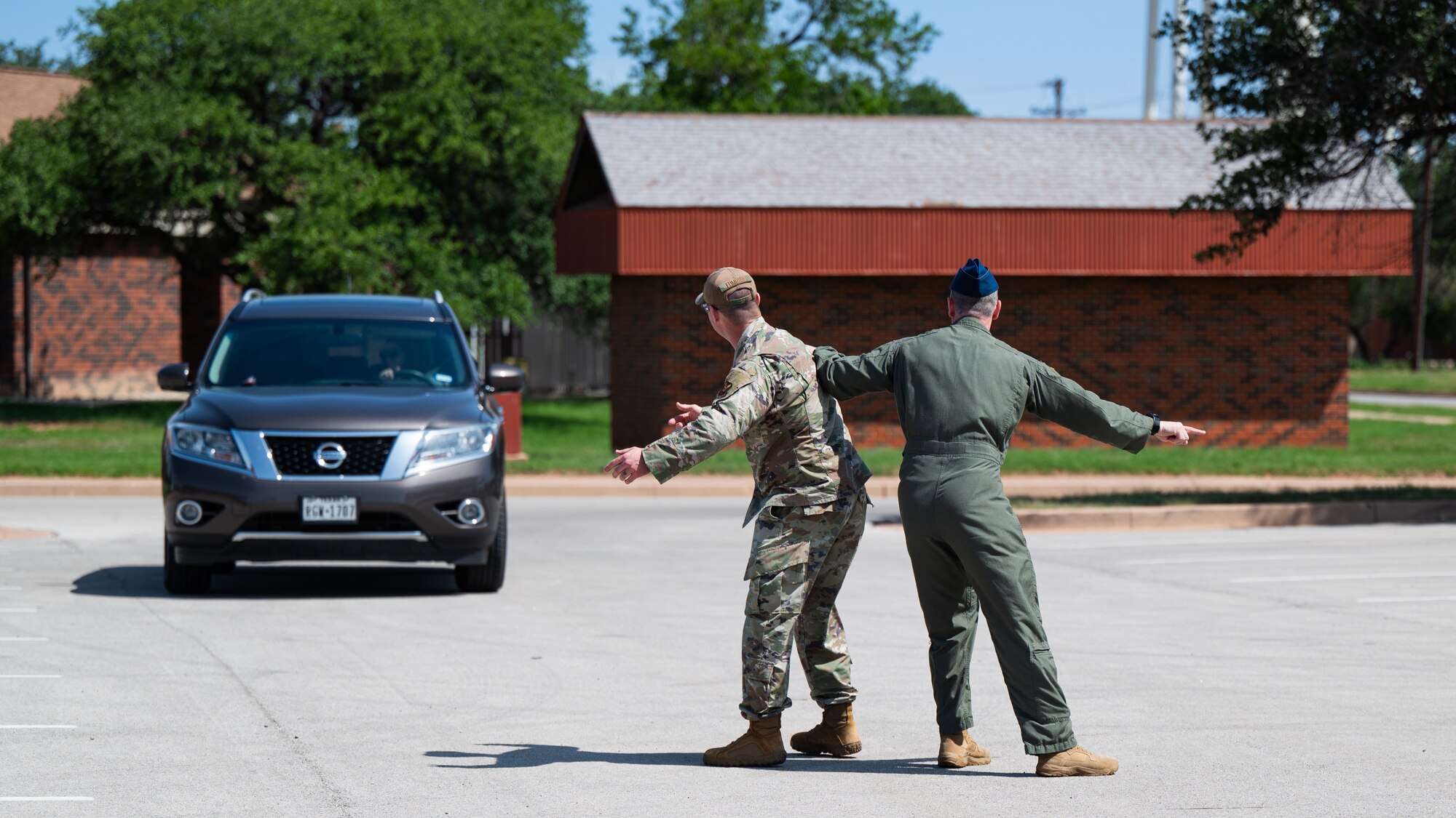 U.S. Air Force Chief Master Sgt. Steven Edmonds, left, 7th Operations Group senior enlisted leader, and Col. Samuel Friend, 7th Bomb Wing deputy commander, compete to get the attention of an event attendee during the Military Spouse Appreciation Day event at Dyess Air Force Base, Texas, May 10, 2024. During the event, volunteers held a friendly competition to see which stand could attract the most attendees. The Department of Defense recognizes the sacrifices that military spouses make for our service members as they endure their own challenges across the world. (U.S. Air Force photo by Airman 1st Class Jade M. Caldwell)