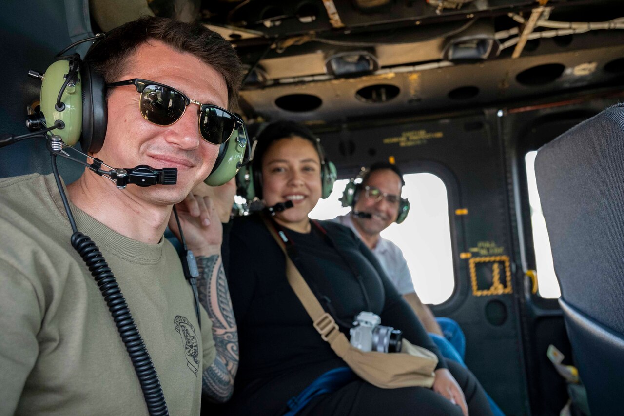 Three people in a helicopter smile at the camera.
