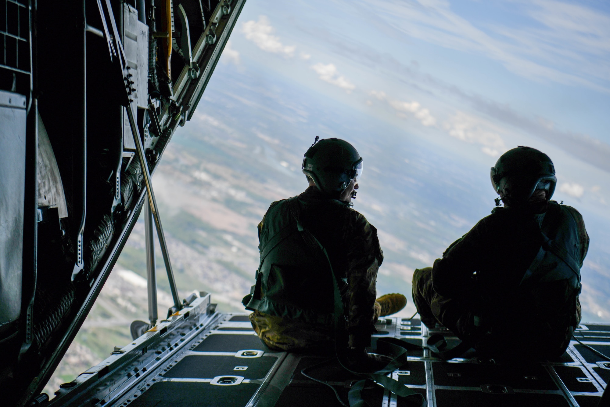 Two loadmasters assigned to the 910th Airlift Wing look out the back of a C-130H Hercules aircraft, during a local educator flight, while circling Niagara Falls, New York, May 10, 2024.