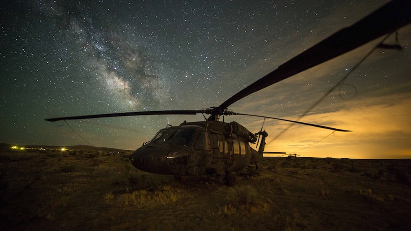 A military helicopter is photographed at night.