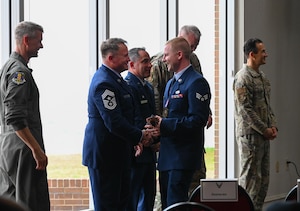 U.S. Air Force Chief Master Sgt. Will Cupp, 350th Spectrum Warfare Wing command chief, left, shakes hands with U.S. Air Force Senior Airman Joel Schlim, 350th Spectrum Warfare Group Detachment One equipment technician, during the Eglin Airman Leadership School graduation at Eglin Air Force Base, Florida, May 9, 2024. Schlim was awarded the Academic Achievement Award and the Distinguished Graduate Award upon completion of ALS. (U.S. Air Force photo by Capt. Benjamin Aronson)