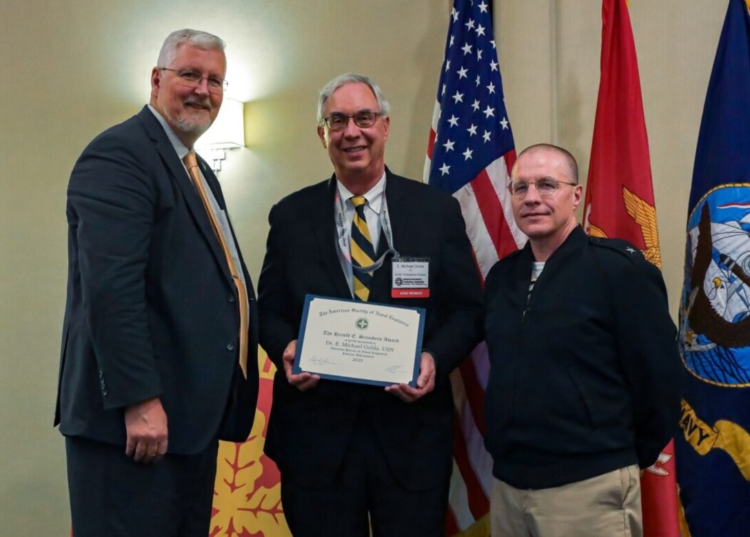 Vice Adm. David Lewis, USN (Ret.) (left) and Chief Engineer and Deputy Commander for Ship Design, Integration and Naval Engineering, SEA-05, Naval Sea Systems Command Rear Adm. Jason Lloyd (right) present the Harold E. Saunders (Lifetime Achievement) Award to Dr. E. Michael Golda (middle) for his dedication and lifetime contributions to the U.S. Navy. The event took place during the 2024 American Society of Naval Engineers (ASNE) Advanced Machinery Technology Symposium (AMTS), held at the Delta Hotel Philadelphia Airport in Philadelphia on May 1-2, 2024. (U.S. Navy Photo by Jay Butterbaugh/Released)