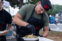 A U.S. Marine with Marine Medium Tiltrotor Squadron (VMM) 363, Marine Aircraft Group 24, 1st Marine Aircraft Wing, prepares tacos for a customer during the 2024 Tacolympics, a cooking and fundraising event, Marine Corps Base Hawaii, May 3, 2024. The contest provided MCBH units an opportunity to compete and raise funds towards their unit Marine Corps Birthday Balls, while celebrating Hispanic culture and diversity. (U.S. Marine Corps photo by Lance Cpl. Tania Guerrero)