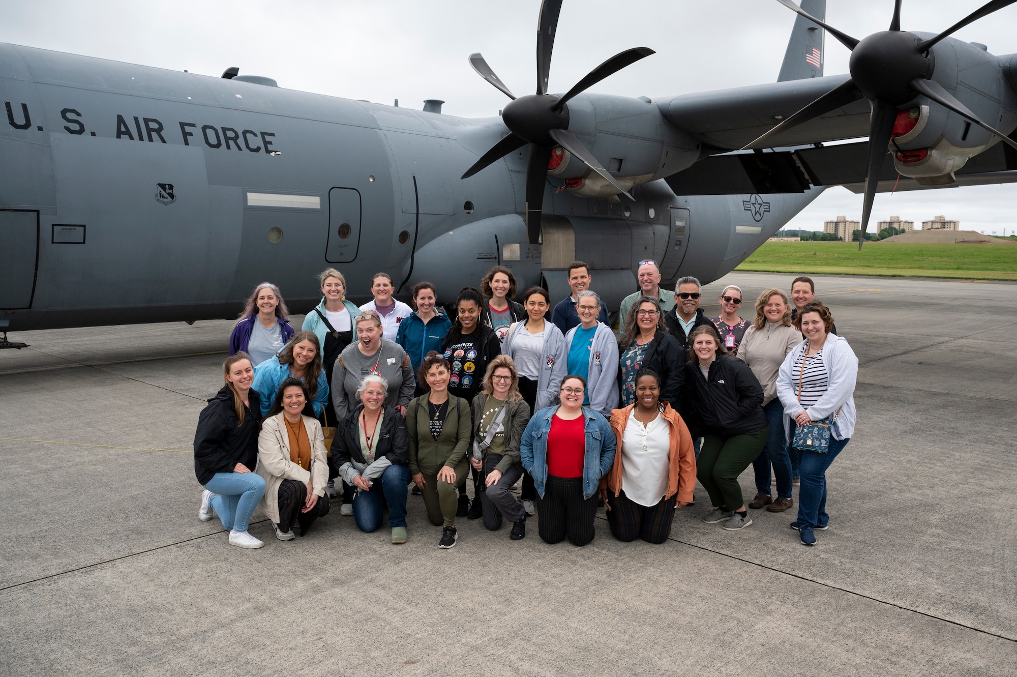Teachers pose for a photo in front of a C-130J Super Hercules.