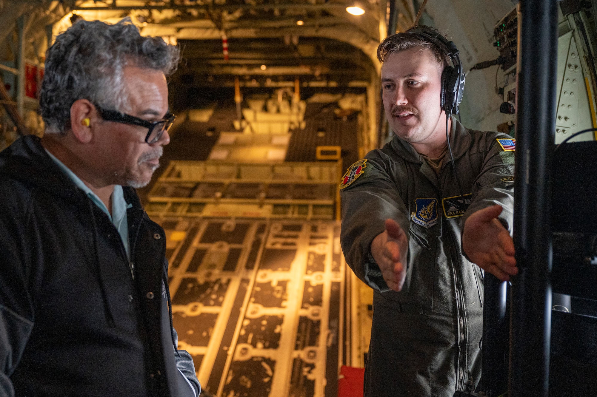 A loadmaster talks to a teacher inside a C-130J Super Hercules.