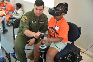 1st. Lt. Mike Dolan, 41st Flying Training Squadron T-6 instructor pilot, helps a participant with a flight simulator while volunteering at Eyes Above the Horizon on April 27, 2024, at Columbus-Lowndes County Airport, Columbus, Mississippi. The program focused on underrepresented communities and youth aged 10-19.