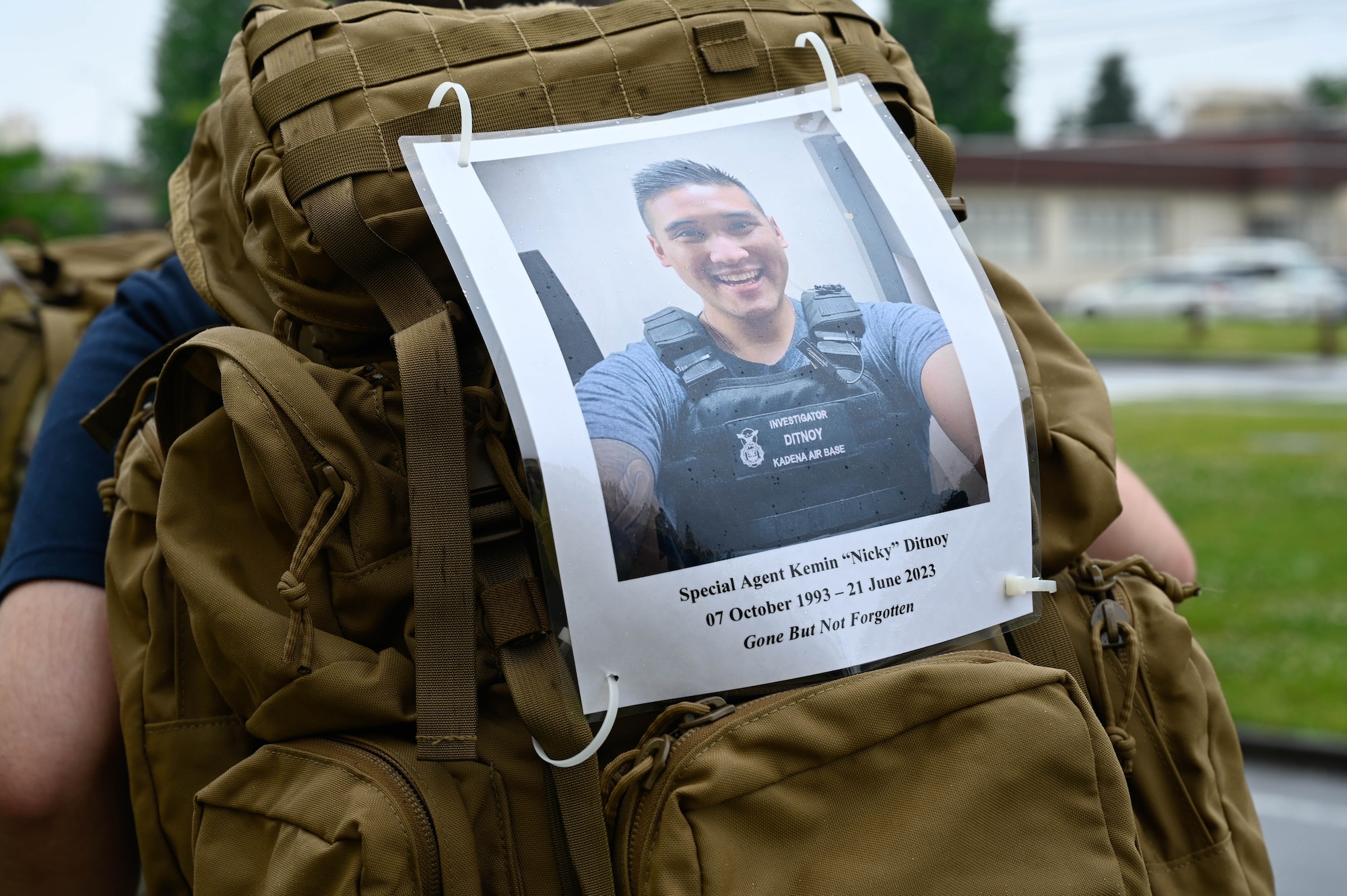 A memorial photo is displayed on a service member's rucksack.