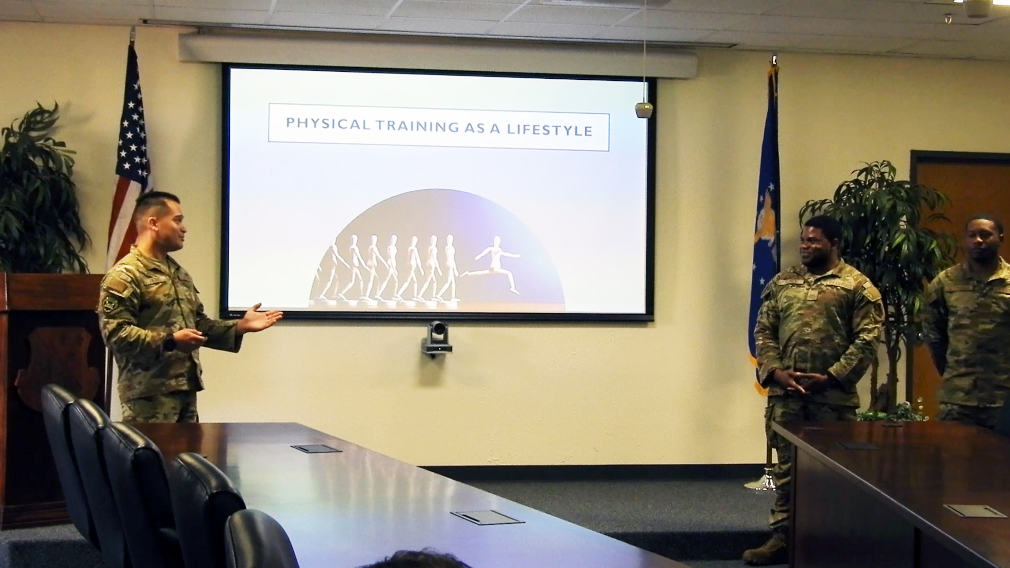 Three Airman stand in front of a screen.