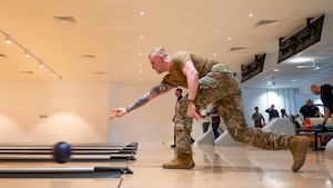 An Airman releases a bowling ball