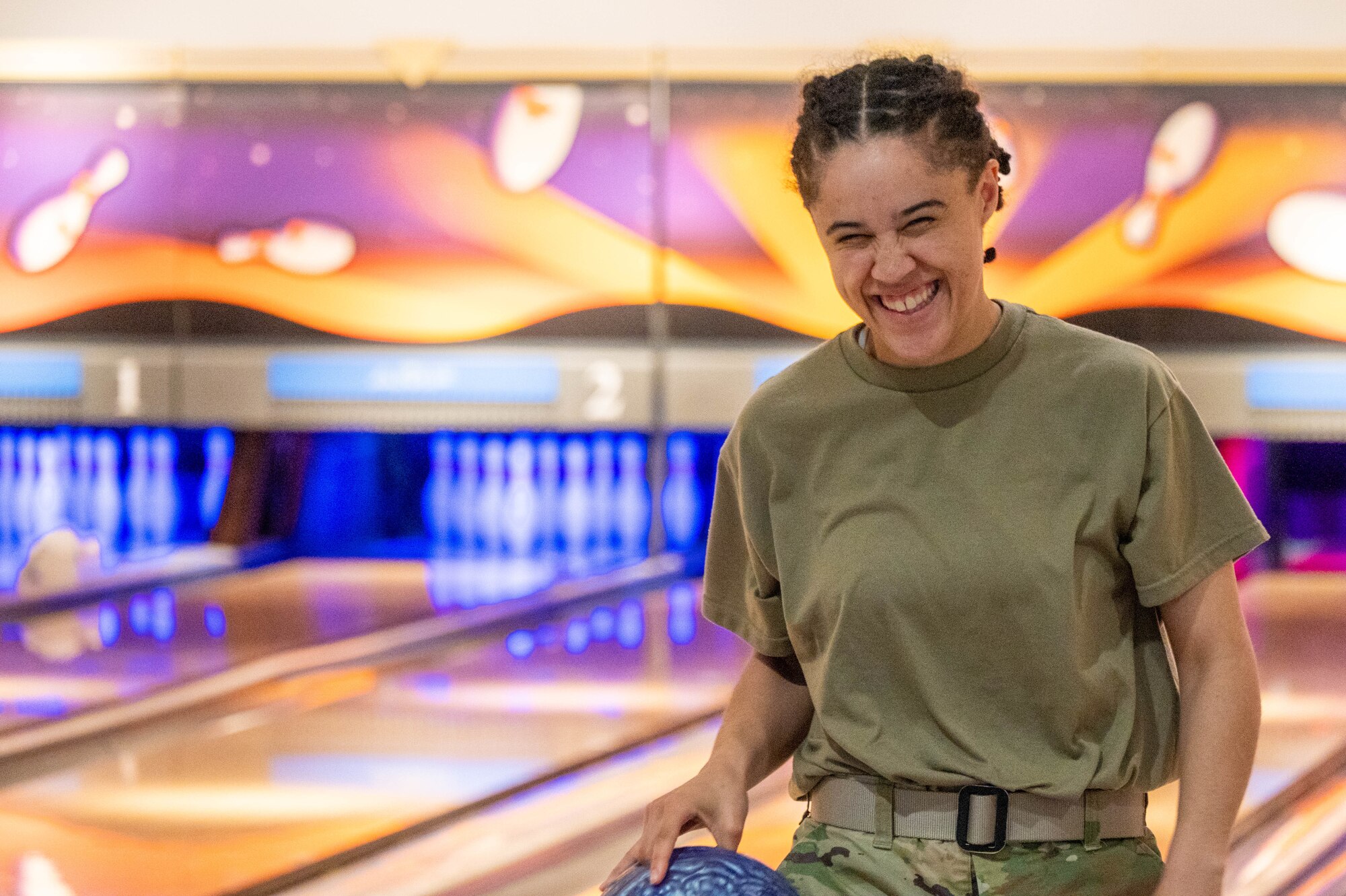 An Airman smiles while holding a bowling ball
