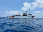 A rustic vessel is approached by a Coast Guard small boat. The boat is pictured again alongside the CGC Seneca.