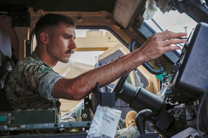 A Marine works inside a vehicle.