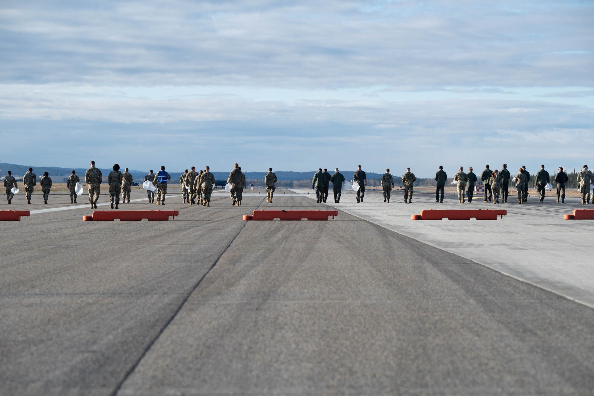 Airmen walk the flightline looking for foreign object debris.
