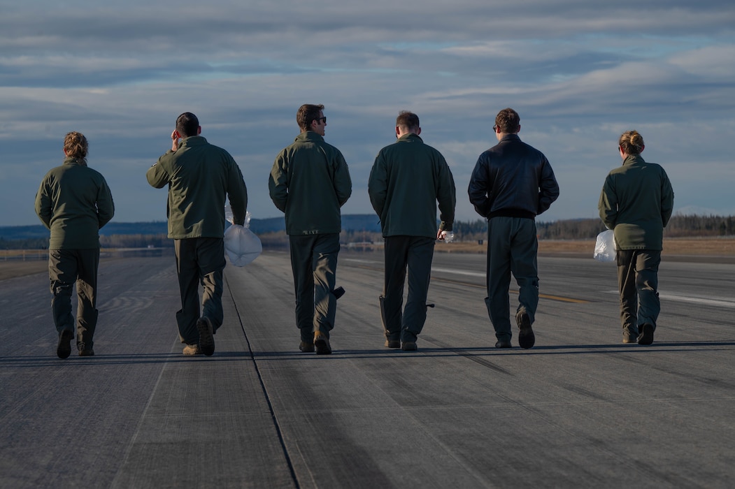 Airmen walk the flightline looking for foreign object debris.
