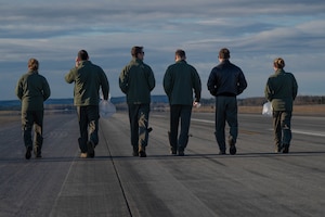 Airmen walk the flightline looking for foreign object debris.
