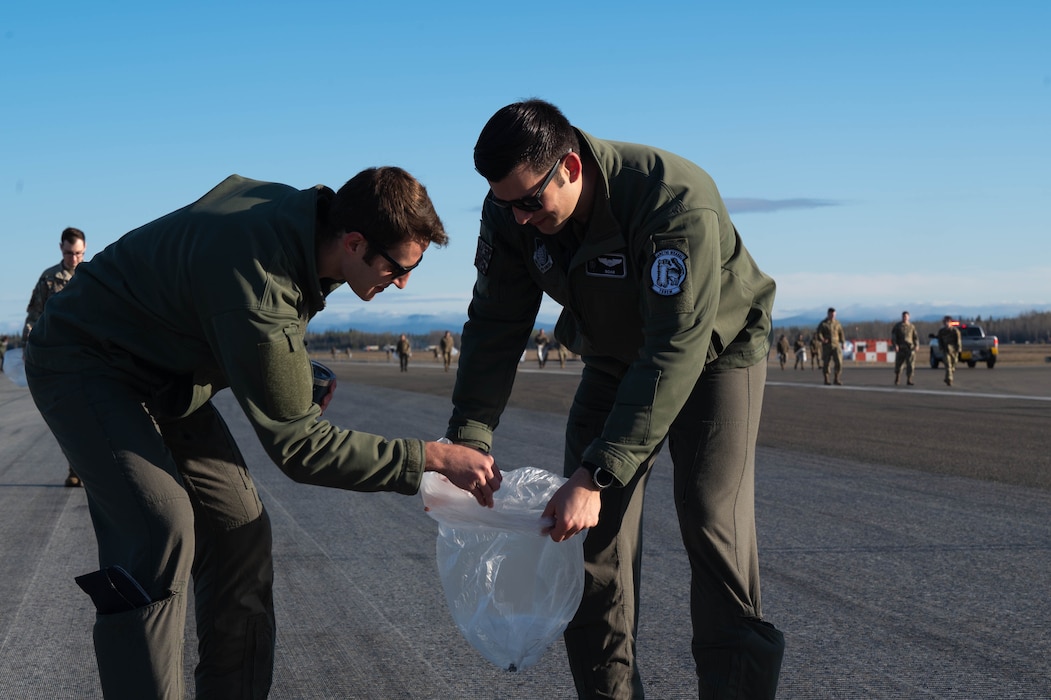 Airmen work together to collect trash on the flightline.