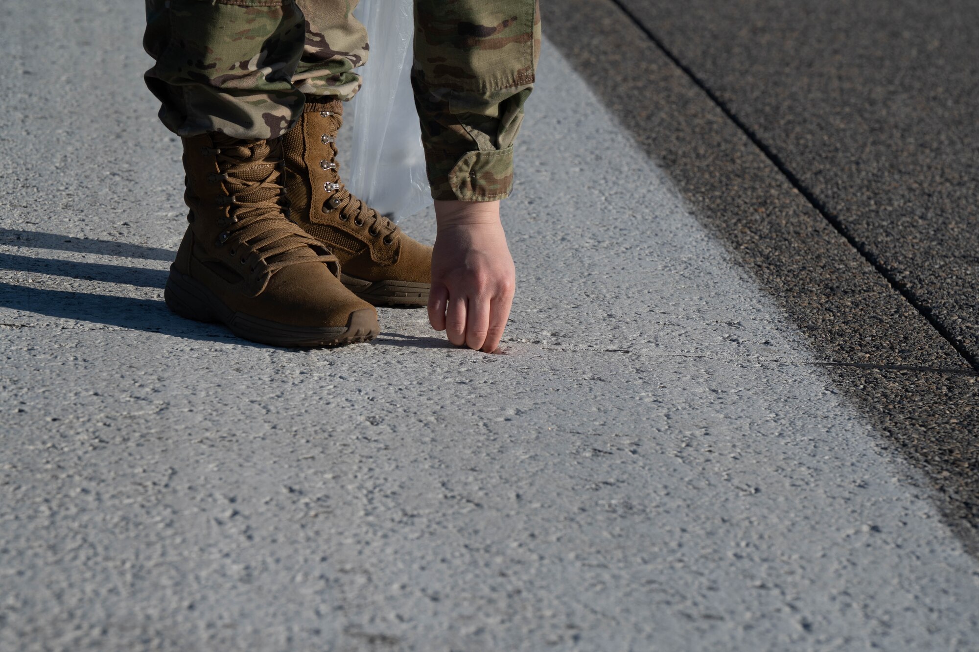 An Airman picks up a piece of trash on the flightline.