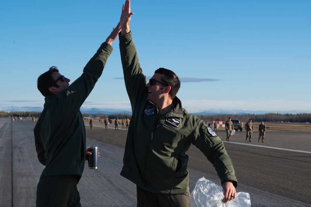 Airmen high five during a foreign object debris walk.