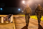 Tech. Sgt. Christopher Duplisea, 802nd Security Forces Squadron mobility and readiness NCO in charge, and Tech. Sgt. Brandon Galindo, 802nd SFS flight sergeant, walk on a track during their two-hour volunteer shift as part of a 24-hour ruck march and candlelight vigil in celebration of National Police Week at Joint Base San Antonio-Lackland, Texas, on May 14, 2024. Candlelit posters of defenders who lost their lives in the line of duty were lined up along the path. National Police Week salutes law enforcement officers who dedicate their lives to the service of others as they work to maintain public safety. (U.S. Air Force photo by Brian Boisvert)