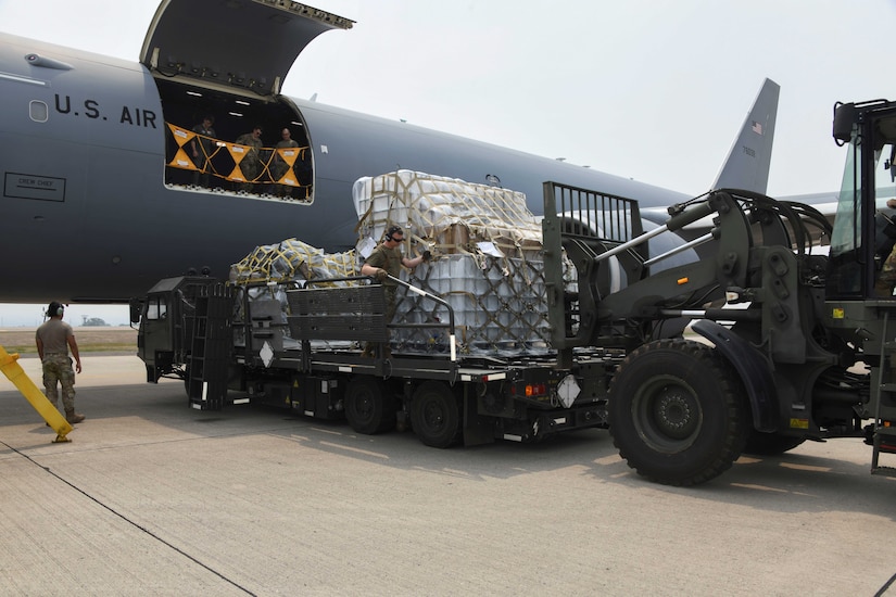 Airmen offload pallets of supplies from a large aircraft.