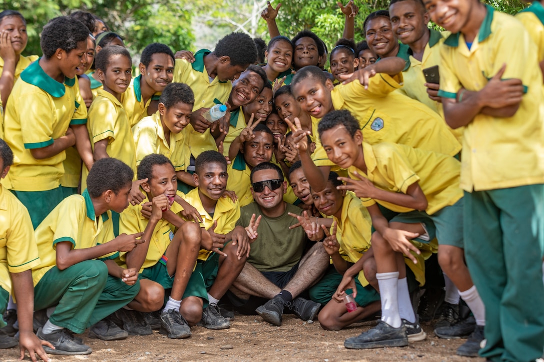 U.S. Marine Corps Sgt. Rodolfo Sandoval, center, a radio operator with Marine Rotational Force – Darwin 24.3, poses for a picture with Taurama Primary School students during a community relations event as part of a humanitarian assistance and disaster relief exercise at Taurama Primary School, Taurama Barracks, Papua New Guinea, May 7, 2024. MRF-D 24.3 Marines and Sailors participated in the event to build stronger relationships within the local community. The HADR exercise is conducted in coordination with the Papua New Guinea Defence force and U.S. Embassy in Port Moresby, with a focus on projecting select role II medical, logistics, and Marine Air-Ground Task Force command and control capabilities off-continent, to validate HADR training and readiness. Sandoval is a native of California. (U.S. Marine Corps photo by Cpl. Migel A. Reynosa)