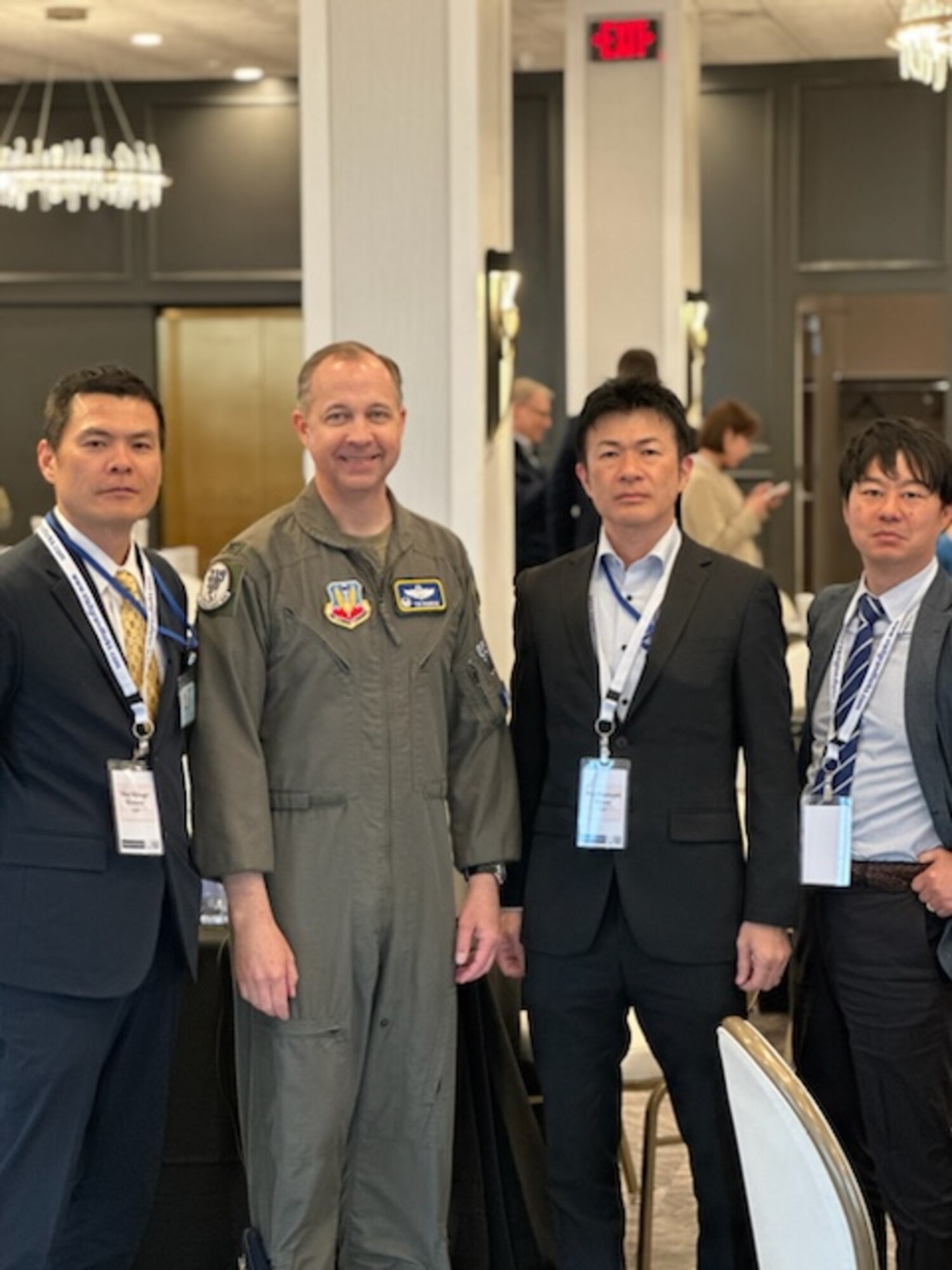 Military members and civilians in suits pose for a group photo.