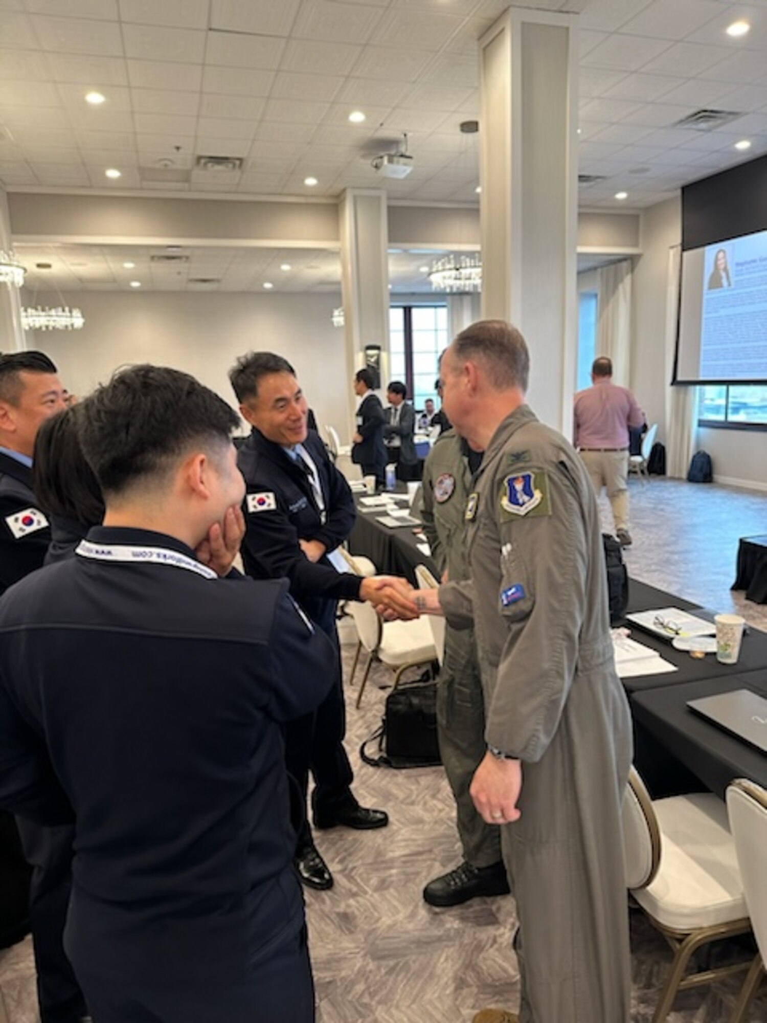 Military members from different countries shake hands.