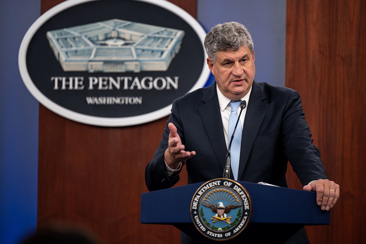 A person in a suit stands at a lectern.