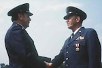 Gen. Robert E. Huyser, commander, Military Airlift Command, congratulates Chief Warrant Officer James H. Long upon his retirement at McGuire Air Force Base, New Jersey, on July 31, 1980. Long, who served more than 29 years with the armed forces, was the last warrant officer in the U.S. Air Force.