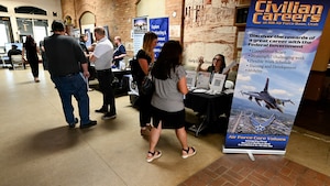 Attendees speak to HR specialists sitting behind an information booth about jobs at Hill AFB.