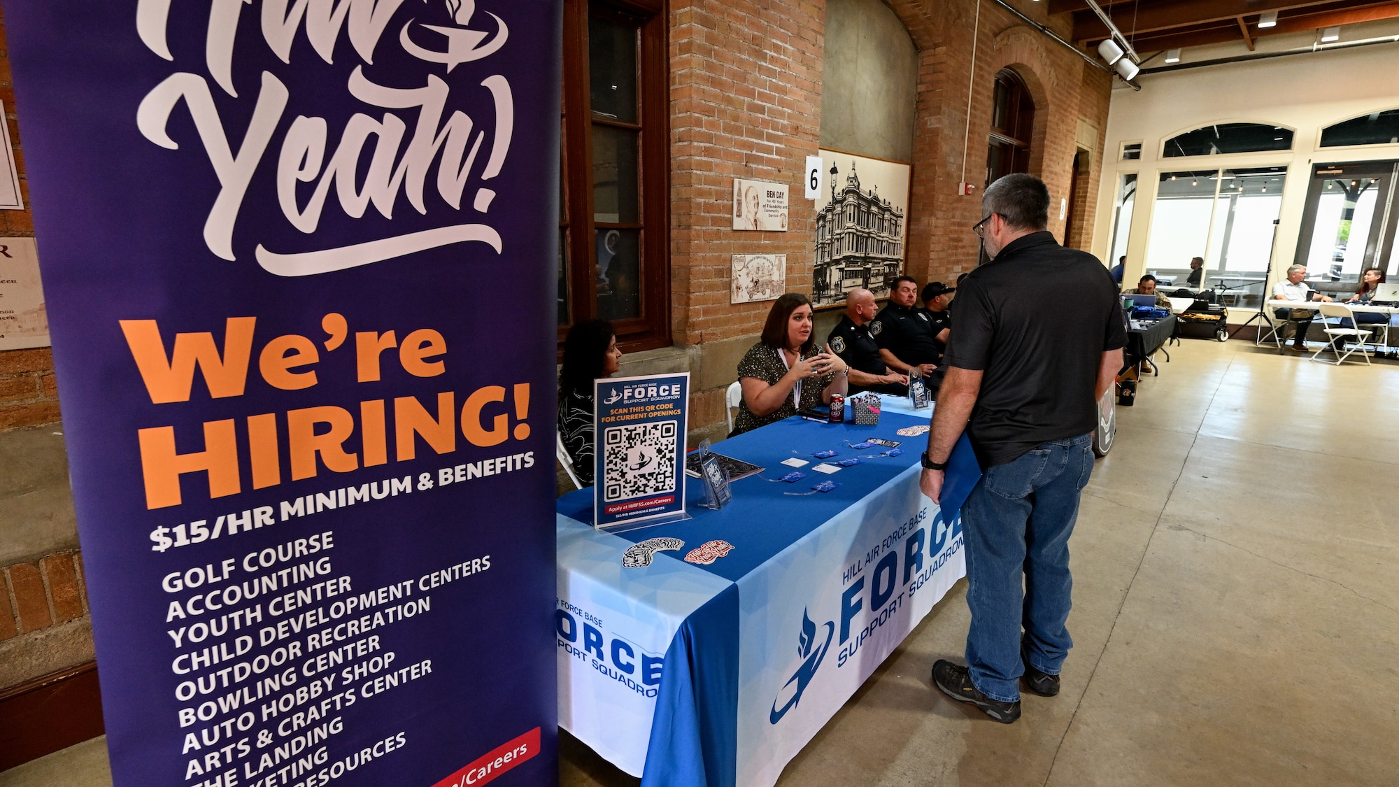 A man speaks to HR specialists sitting behind an information booth about jobs at Hill AFB.