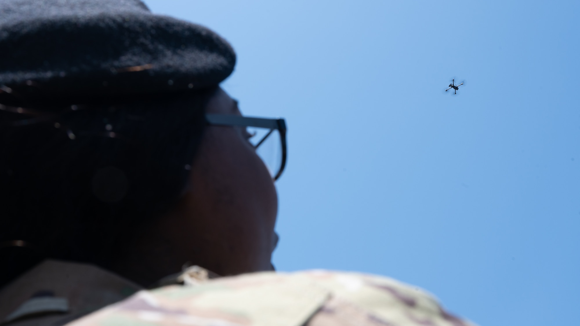 Senior Airman Amira Barnes looks up at a drone she is operating.