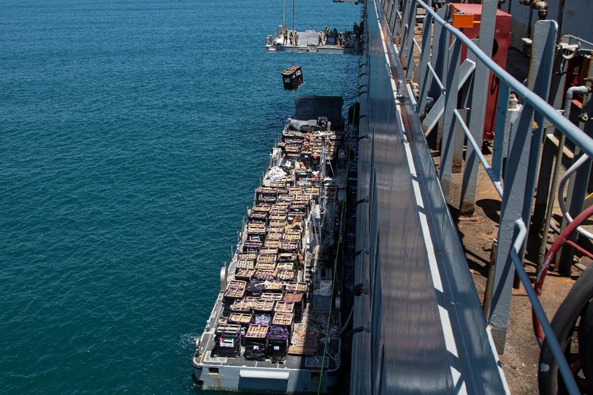 A crane lifts cargo from a boat to a pier.